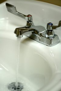 Silver faucet with water coming out.
