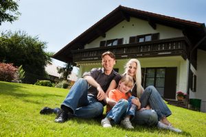 Family sitting on grass hill in front of house