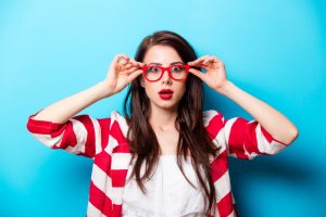 Surprised woman holding on her red glasses